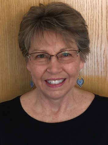 A woman with glasses smiling for the camera.