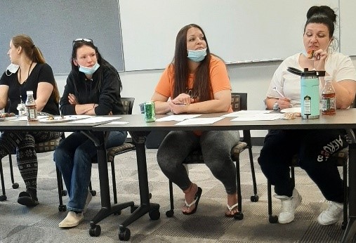 A group of people sitting at a table with masks on.